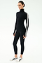 A person wears the SPLITS59 Jackson Rib Full Length Turtleneck in Black/White, paired with black leggings and white sneakers, standing against a plain white background.