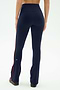 A person faces away, wearing SPLITS59 Raquel High Waist Flared Legging in Indigo/Dark Cherry—a navy flared nylon-spandex pant with maroon side stripe—paired with dark shoes against a plain white background.
