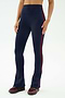 A person models SPLITS59's Raquel High Waist Flared Legging in Indigo/Dark Cherry, featuring a flared silhouette and side stripe, paired with burgundy sneakers against a plain background.