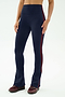 A person models SPLITS59's Raquel High Waist Flared Legging in Indigo/Dark Cherry, featuring a flared silhouette and side stripe, paired with burgundy sneakers against a plain background.