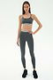 A woman wears the SPLITS59 Cali Active Rib Bra in Heather Grey with matching leggings and black sneakers against a plain white background.