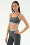 A woman poses with one hand on her hip, wearing the SPLITS59 Cali Active Rib Bra in Heather Grey and matching athletic bottoms with white and black stripes, set against a plain white background.