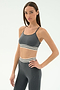 A woman poses with one hand on her hip, wearing the SPLITS59 Cali Active Rib Bra in Heather Grey and matching athletic bottoms with white and black stripes, set against a plain white background.