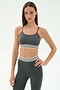 A woman in the SPLITS59 Cali Active Rib Bra in Heather Grey stands against a plain light background, paired with matching high-waisted leggings featuring white and black stripes.