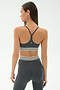 A woman is shown from the back wearing the SPLITS59 Cali Active Rib Bra in Heather Grey with matching high-waisted leggings, both featuring white and black striped bands.