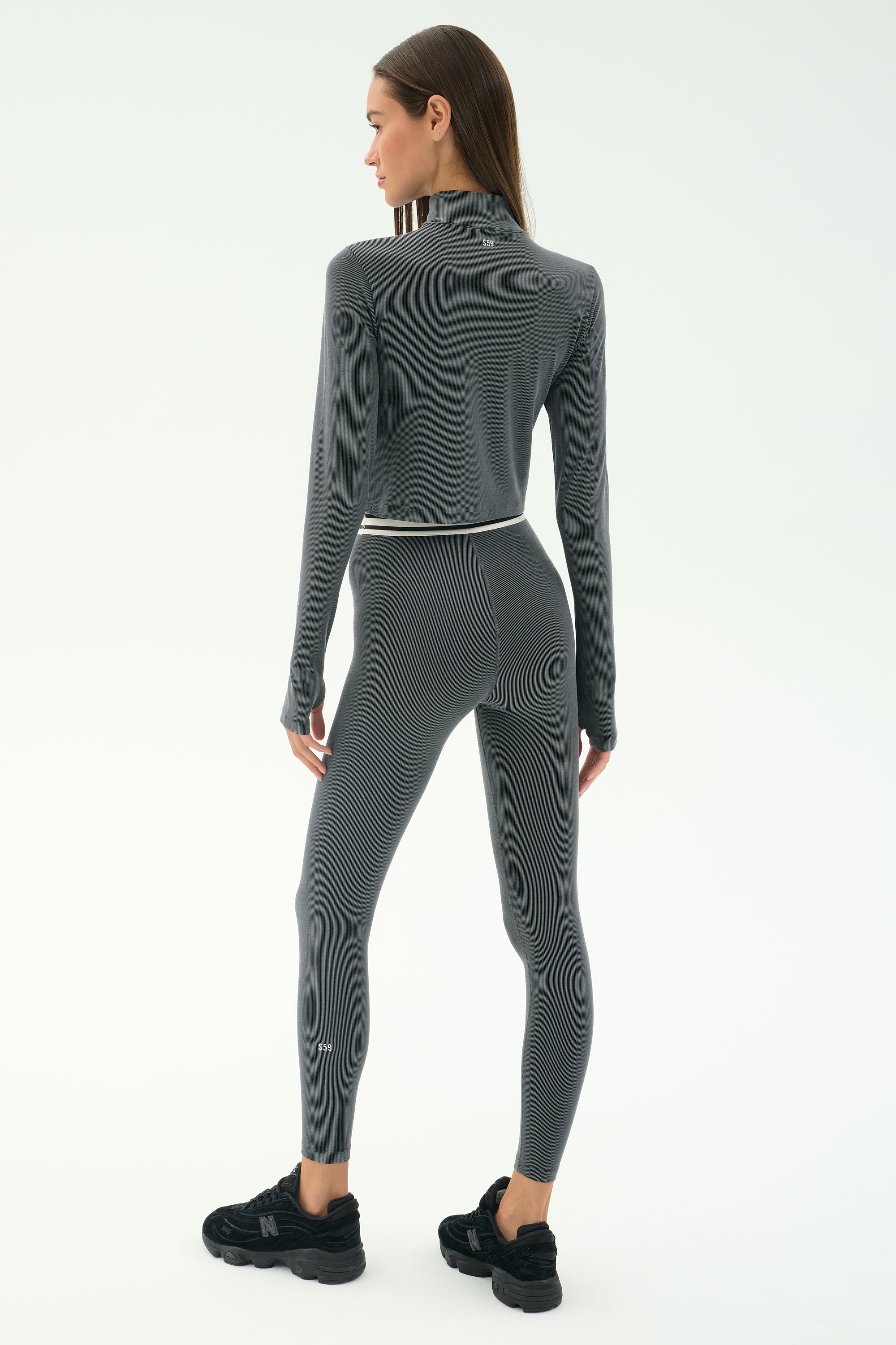 A woman wearing the SPLITS59 Bailey Active Rib High Waist 7/8 leggings in Heather Grey—ideal for gym workouts.