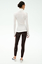 A woman stands with her back to the camera, wearing a white SPLITS59 Jackson Rib Full Length Turtleneck and dark leggings—perfect for yoga or running—paired with white athletic shoes against a plain background.