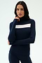 A woman stands against a plain light background wearing the SPLITS59 Lennon Rib Turtleneck in Indigo/White, featuring a navy blue ribbed design with a white horizontal stripe across the chest.