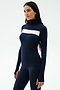 A woman stands against a plain light background wearing the SPLITS59 Lennon Rib Turtleneck in Indigo/White, featuring a fitted silhouette and white horizontal chest stripe, paired with matching navy leggings.