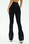 A person stands with their back to the camera against a plain white background, wearing SPLITS59 Raquel High Waist Flared Legging in Black/Creme and white sneakers.