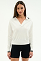 A woman stands against a plain white background wearing the SPLITS59 Taylor Knit Polo in white with black trim and black shorts.