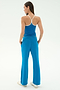 A woman stands with her back to the camera, wearing the SPLITS59 Airweight Tank in Stone Blue/White and matching wide-leg pants—ideal for hot yoga—with hands in pockets, against a plain white background.