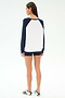 A person stands facing away, wearing the SPLITS59 Andie Oversized Colorblock Fleece in Indigo/White, black shorts, and white sneakers with navy stripes, against a plain white background.
