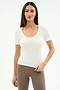 A woman with long straight hair wears the SPLITS59 Ashby Rib Short Sleeve in white and high-waisted brown leggings, standing against a plain light background.