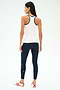 A woman faces away, wearing the SPLITS59 Ashby Rib Tank in White/Indigo—ideal for yoga or gym—paired with navy blue leggings and white sneakers with red stripes, against a plain white background.