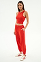 Woman wearing the SPLITS59 Kiki Rib Crop Tank in Lotus Red, paired with red joggers and white Adidas sneakers, standing against a white background. A chic sporty look for street style or gym sessions.