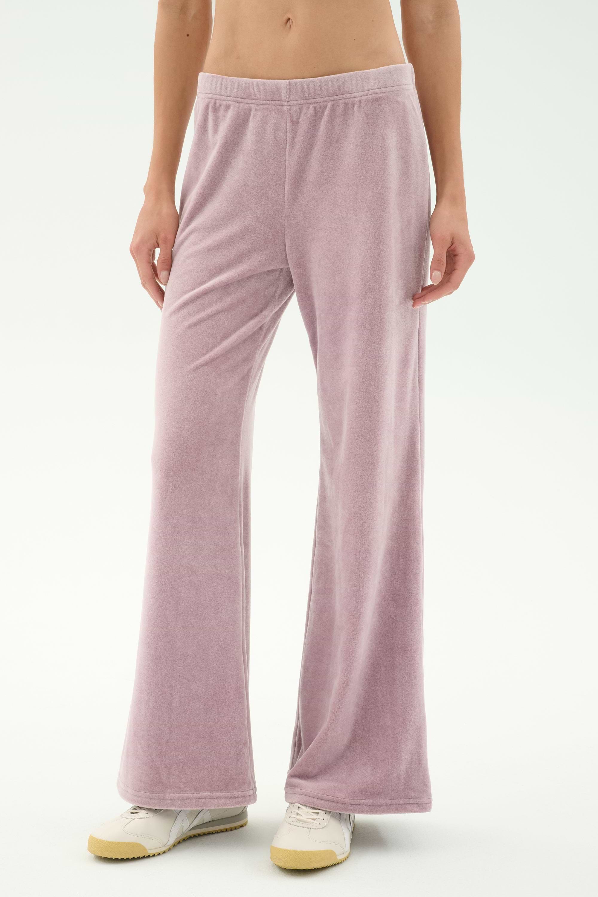 Model wears SPLITS59 Joy Velour Pant in Blush with white sneakers, standing against a plain light background. Upper torso is not visible.