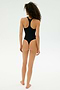 A person with curly hair stands barefoot and facing away, wearing the SPLITS59 Suki Airweight Bodysuit in black against a plain white background—ideal for Pilates or hot yoga.