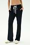 A person in SPLITS59 Raven Fleece Full Length Sweatpant - Black and white sneakers stands with hands in pockets against a plain background.