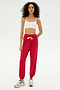 A person stands against a plain background wearing a white crop top, white sneakers, and the SPLITS59 Andie Oversized Fleece Sweatpant in Pirate Red—made from ultra luxe fleece, perfect for cool weather workouts.