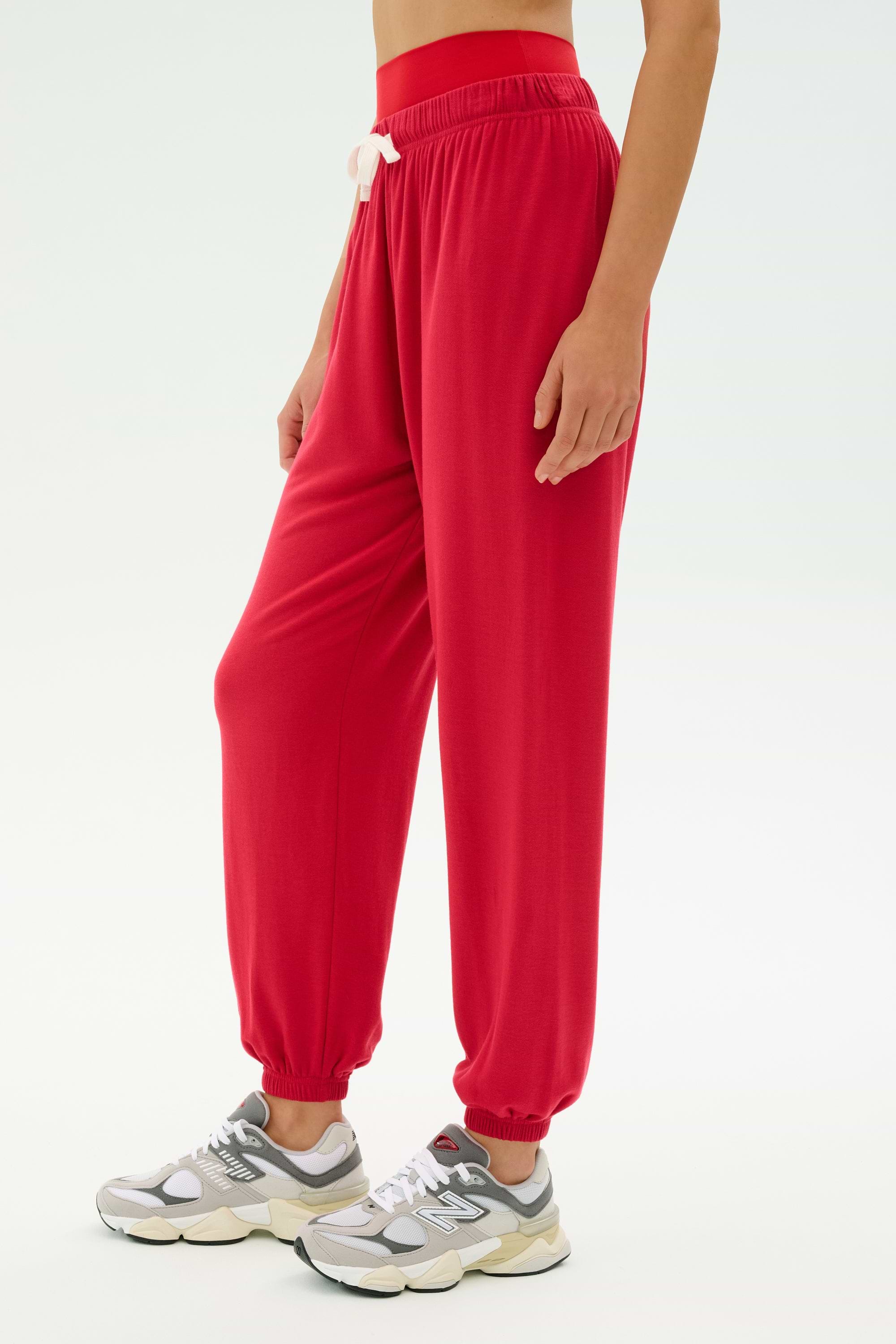 A person wears the SPLITS59 Andie Oversized Fleece Sweatpant in Pirate Red with a crop top and gray sneakers, standing against a plain light background—ideal for cool-weather workouts in ultra-luxe fleece comfort.