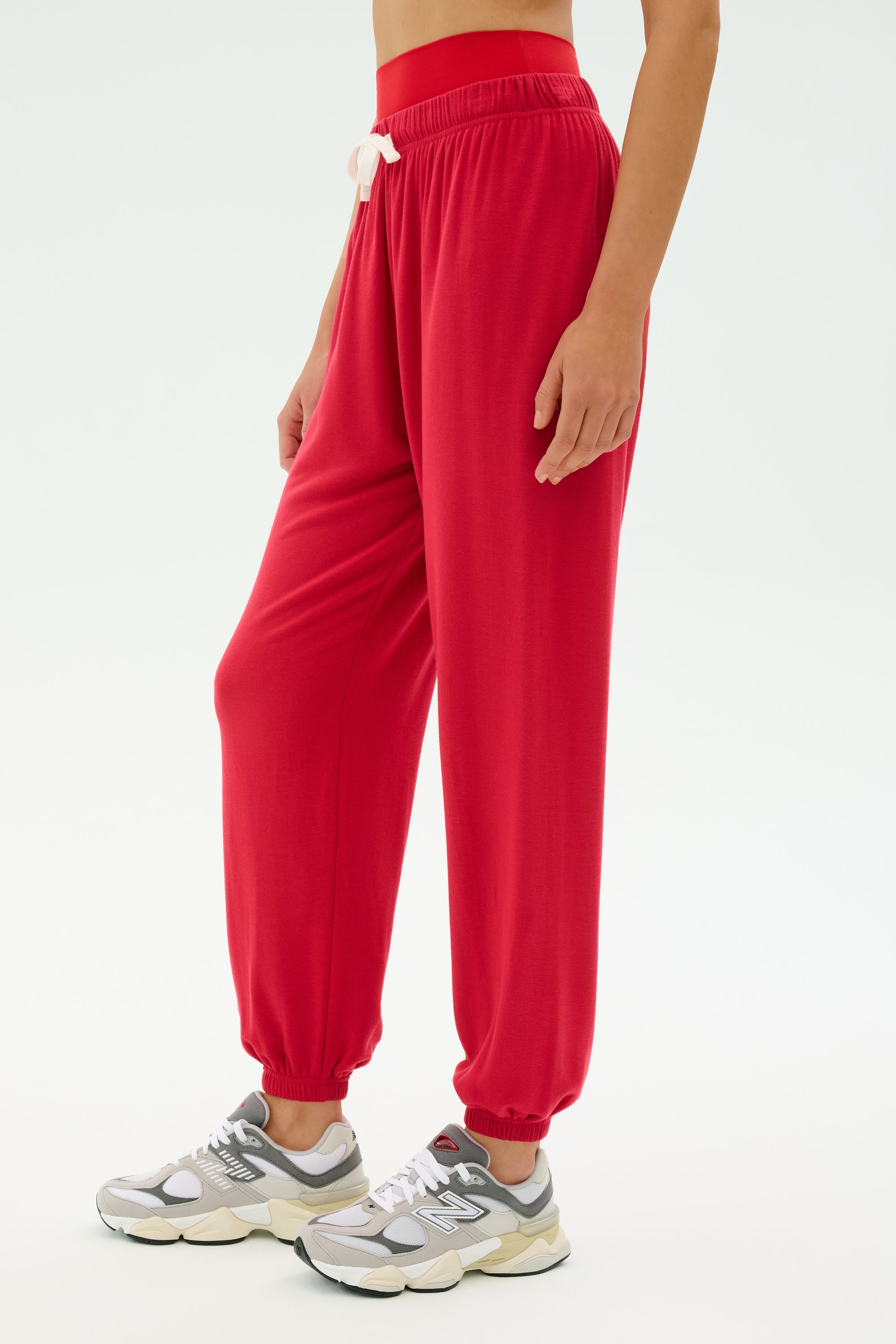 A person wears the SPLITS59 Andie Oversized Fleece Sweatpant in Pirate Red with a crop top and gray sneakers, standing against a plain light background—ideal for cool-weather workouts in ultra-luxe fleece comfort.