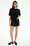 A woman stands against a white background wearing the SPLITS59 Djuna Oversized Jersey Tee in black, paired with black athletic shorts with white trim and black sneakers.