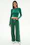 A woman faces forward wearing SPLITS59's Willow Airweight Wide Leg pants in Arugula/White—a spandex set with a green long-sleeve crop top and white sneakers—against a plain background.