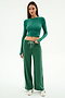 A woman faces forward wearing SPLITS59's Willow Airweight Wide Leg pants in Arugula/White—a spandex set with a green long-sleeve crop top and white sneakers—against a plain background.