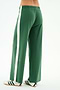 A person models SPLITS59’s Willow Airweight Wide Leg pants in Arugula/White with white sneakers featuring black stripes, standing against a white background.