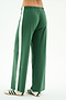 A person models SPLITS59’s Willow Airweight Wide Leg pants in Arugula/White with white sneakers featuring black stripes, standing against a white background.