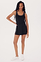 A person with long hair stands in a black sleeveless Martina Rigor Dress w/Piping - Black by SPLITS59 and white sneakers, posing against a plain white background.