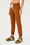Full front view of woman wearing dark orange sweatpant jogger with white drawstring paired with dark green, orange and light green shoes