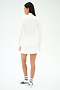 A woman faces away, wearing the SPLITS59 Stevie Active Rib Half Zip Waist Length top in white, styled with a matching skirt, white socks, and white sneakers with black details against a plain white background.
