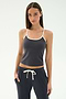 A woman in the SPLITS59 Airweight Tank - Graphite/White stands with her hands in her pockets, wearing matching drawstring pants and ready for Pilates against a plain background.