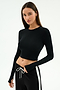 A woman wears the SPLITS59 Louise Rib Long Sleeve Crop in black, paired with black athletic pants featuring a white drawstring and side stripe, standing against a plain white background.