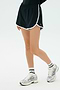 A person wears the SPLITS59 Megan Woven Nylon Run Short in Black with white trim, white socks, and silver running shoes, standing against a plain light background.