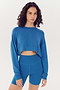 Woman in a SPLITS59 Noah Fleece Crop Sweatshirt - Stone Blue and matching shorts, both made from a modal spandex blend.