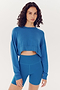 Woman in a SPLITS59 Noah Fleece Crop Sweatshirt - Stone Blue and matching shorts, both made from a modal spandex blend.