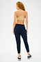 A person with curly hair, wearing a Splits59 Loren Seamless Bra in Nude and navy joggers, standing turned away.