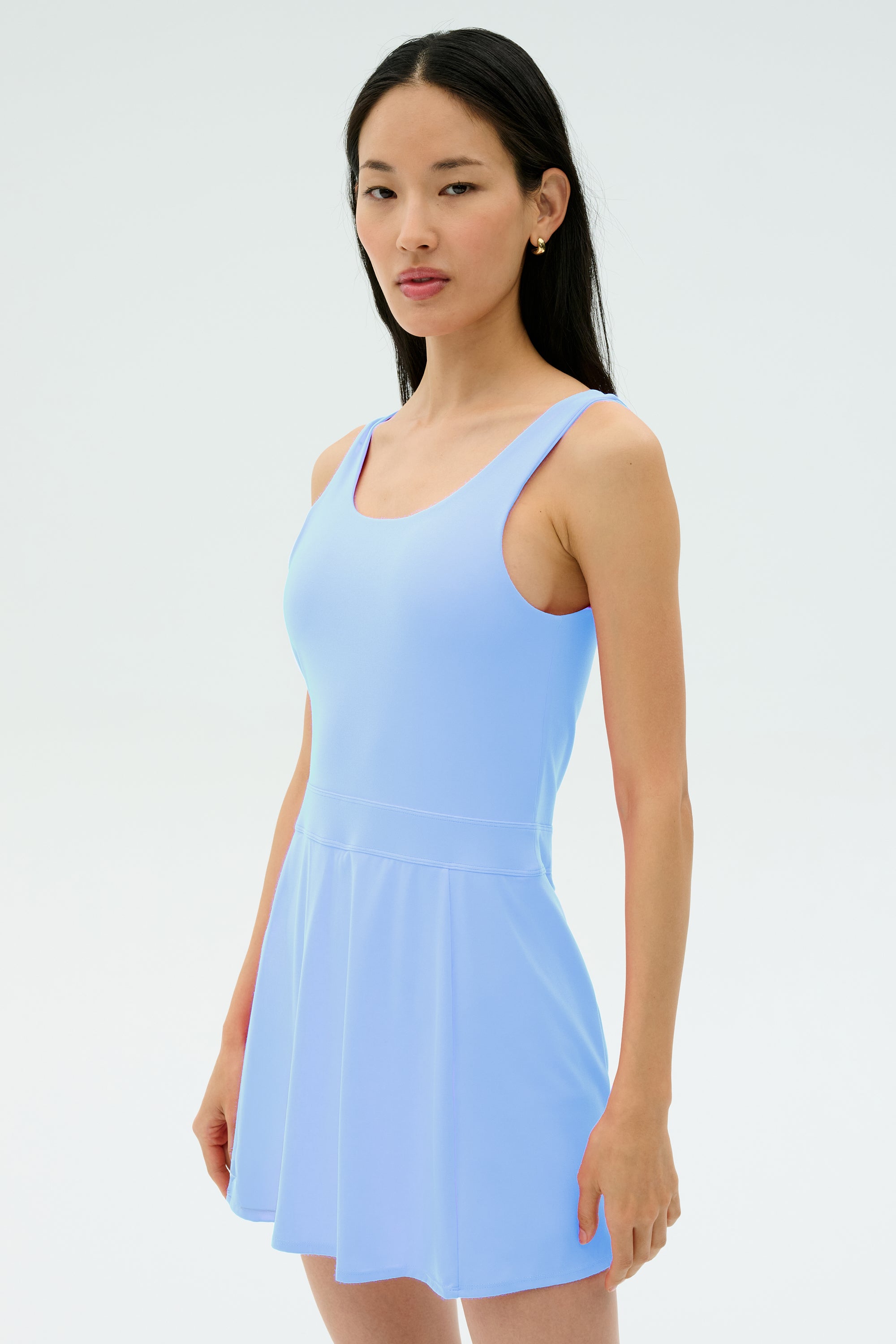 A person with long black hair wears the SPLITS59 Martina Rigor Dress in Skylight, standing against a plain white background.
