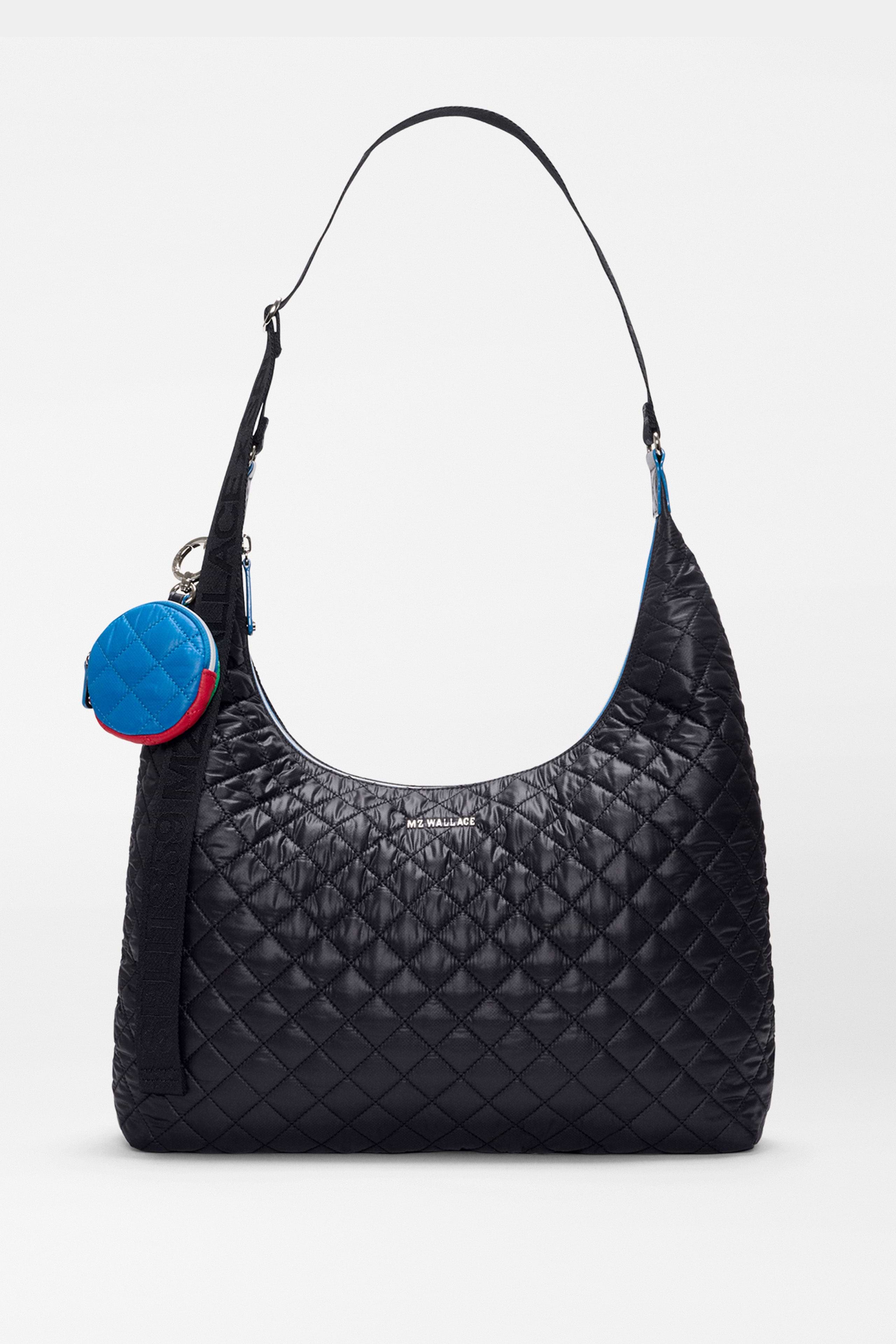 The SPLITS59 MZW x Splits59 Carry All is a black quilted shoulder bag featuring a curved strap and a small, round blue-and-red coin pouch attached to the handle.