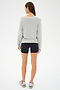 A person wearing a versatile pullover, SPLITS59's Bennie Fleece V-Neck Sweatshirt in Heather Grey/White, black shorts, and sneakers is standing and facing away.