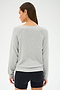 A woman in a SPLITS59 Bennie Fleece V-Neck Sweatshirt in Heather Grey/White and black shorts stands facing away, with her head slightly turned to the left.