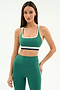 A woman stands against a plain background wearing the SPLITS59 Bianca Rigor Bra in Arugula/White, paired with matching high-waisted green leggings, both crafted from a soft nylon spandex blend.