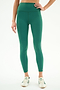 A person wears SPLITS59 Bianca High Waist Rigor 7/8 leggings in Arugula/White with white sneakers, standing against a plain white background.