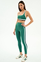 A woman poses against a white background wearing the SPLITS59 Bianca High Waist Rigor 7/8 leggings in Arugula/White and a matching green sports bra, both made from an athletic nylon spandex blend, paired with white sneakers featuring green stripes.