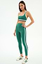 A woman faces forward wearing the SPLITS59 Bianca Rigor Bra in Arugula/White, paired with matching leggings and white sneakers with green stripes, all set against a plain white background.