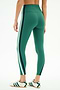 Model wears SPLITS59 Bianca High Waist Rigor 7/8 leggings in Arugula/White, featuring comfy nylon-spandex fabric and white/navy side stripes, paired with white sneakers, standing against a white background.
