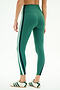 Model wears SPLITS59 Bianca High Waist Rigor 7/8 leggings in Arugula/White, featuring comfy nylon-spandex fabric and white/navy side stripes, paired with white sneakers, standing against a white background.